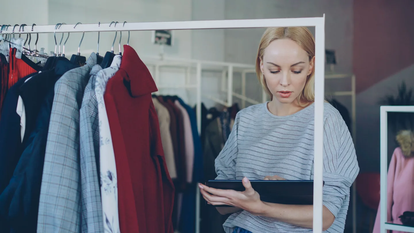 Employée vérifiant le stock avec une tablette dans un magasin de vêtements