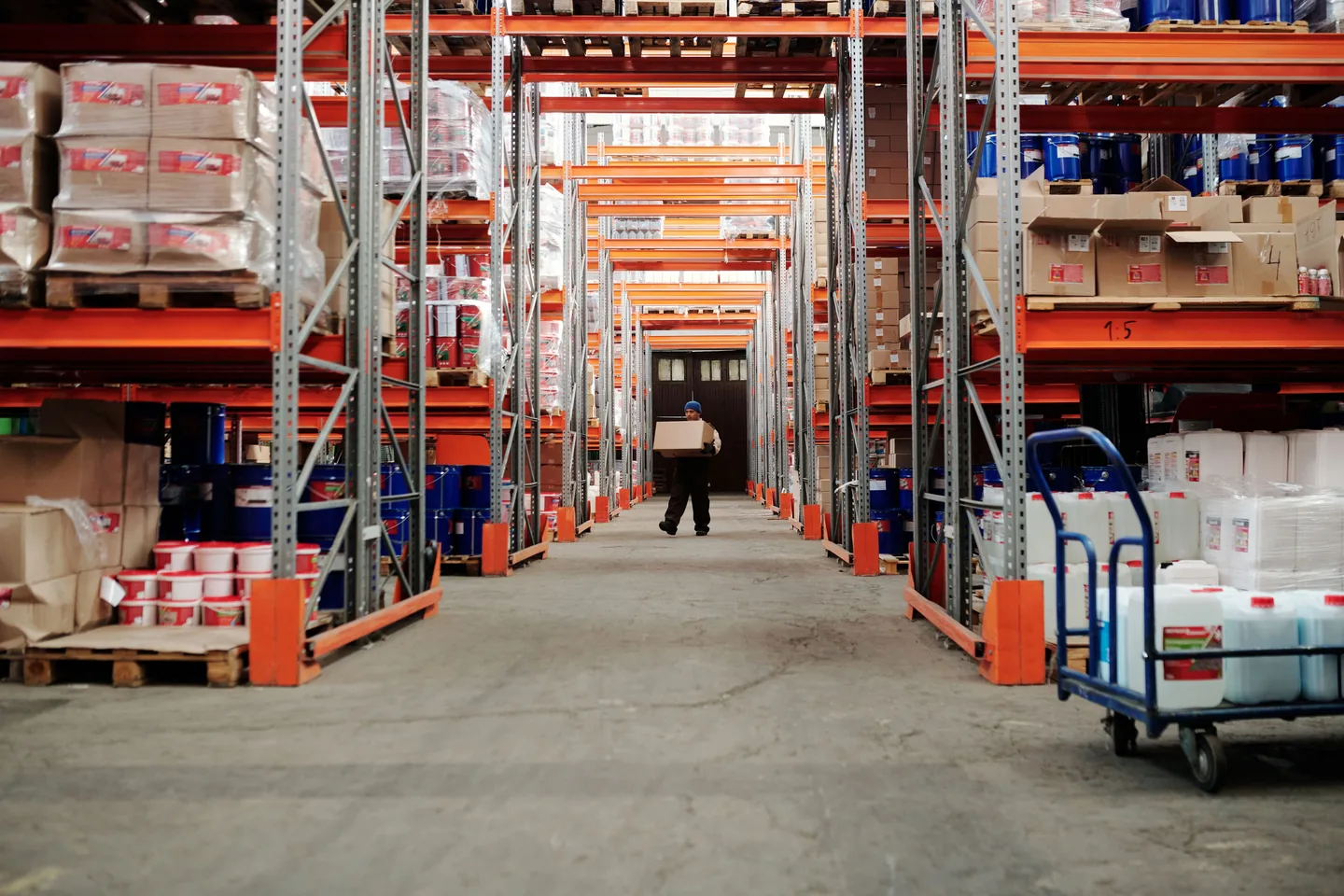 Employé portant un carton entre des rayonnages remplis