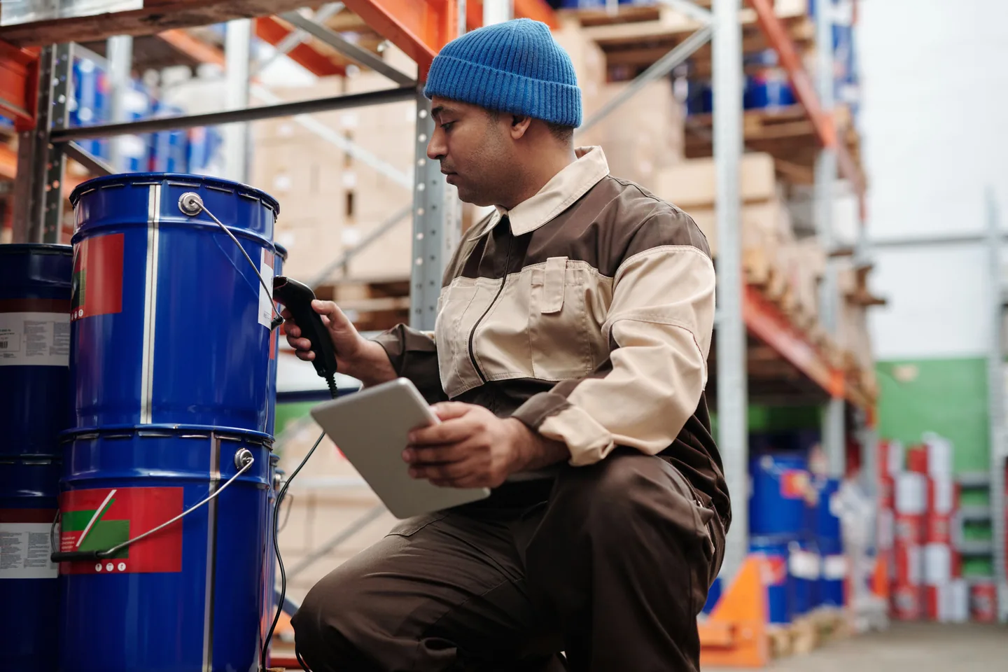 Employé vérifiant la marchandise avec un appareil mobile devant un rayon