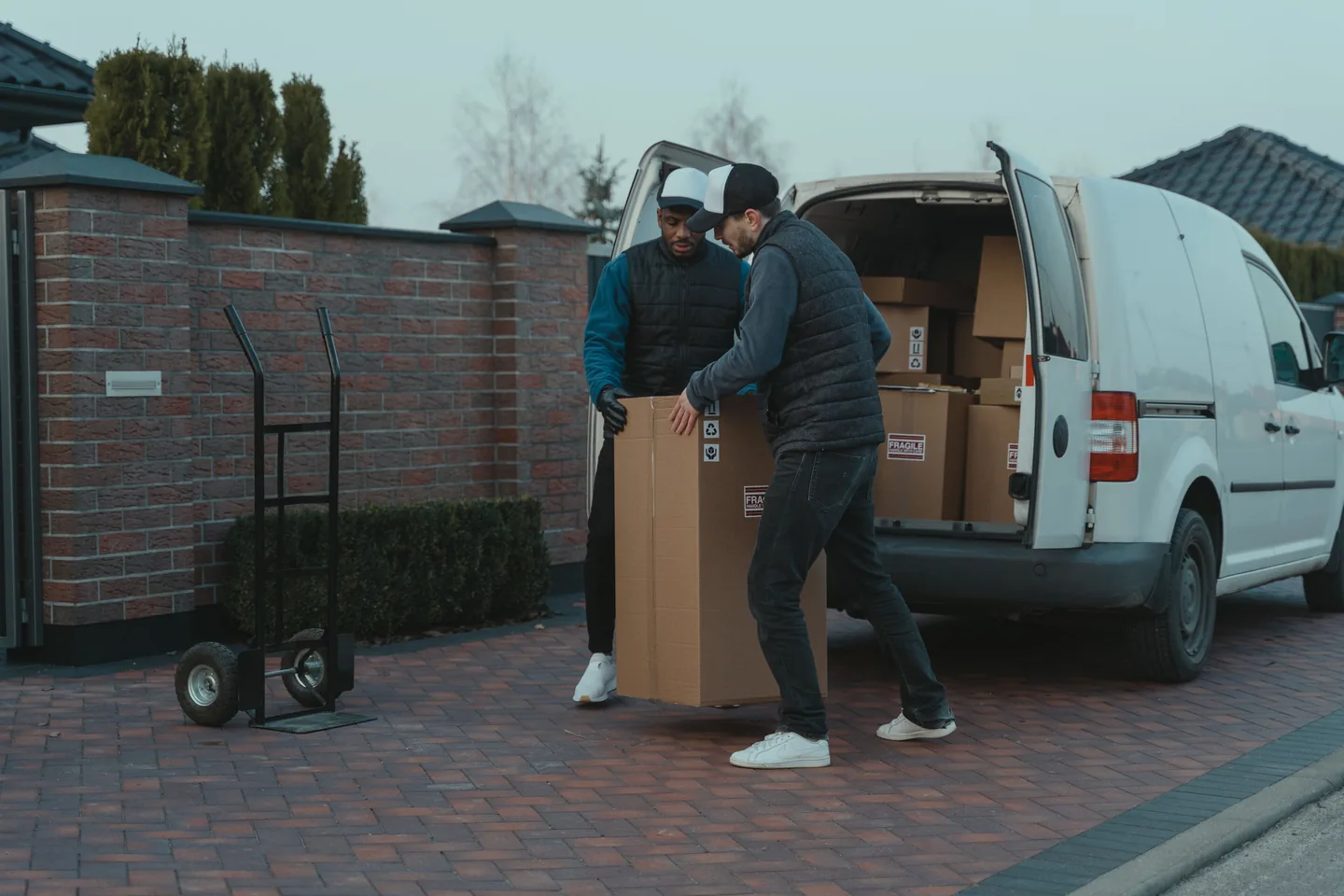 Deux personnes déplaçant un grand carton près d’une camionnette