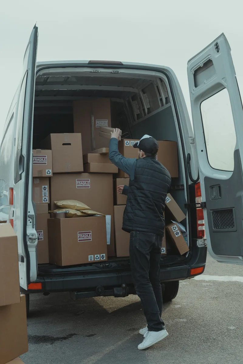 Livreur organisant des cartons près d’une camionnette