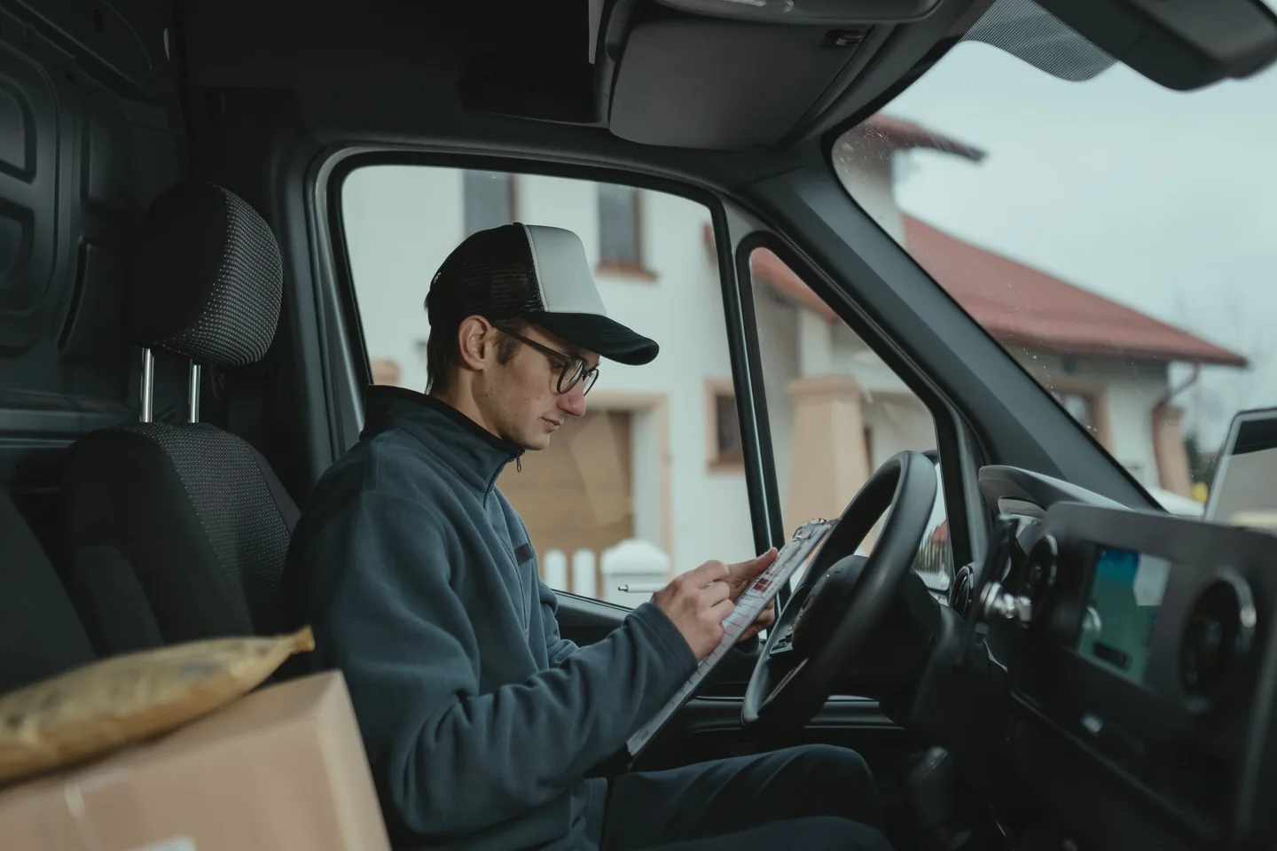 Livreur remplissant des documents au volant d’une camionnette à l’arrêt