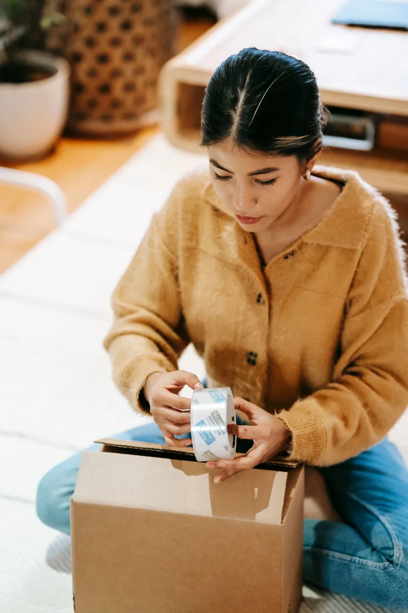 Femme emballant soigneusement de la céramique dans un carton