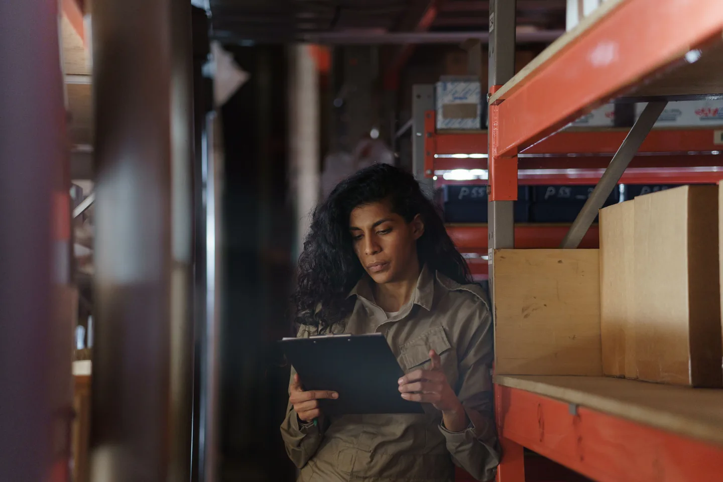 Employée contrôlant la marchandise avec un porte-documents entre des rayons