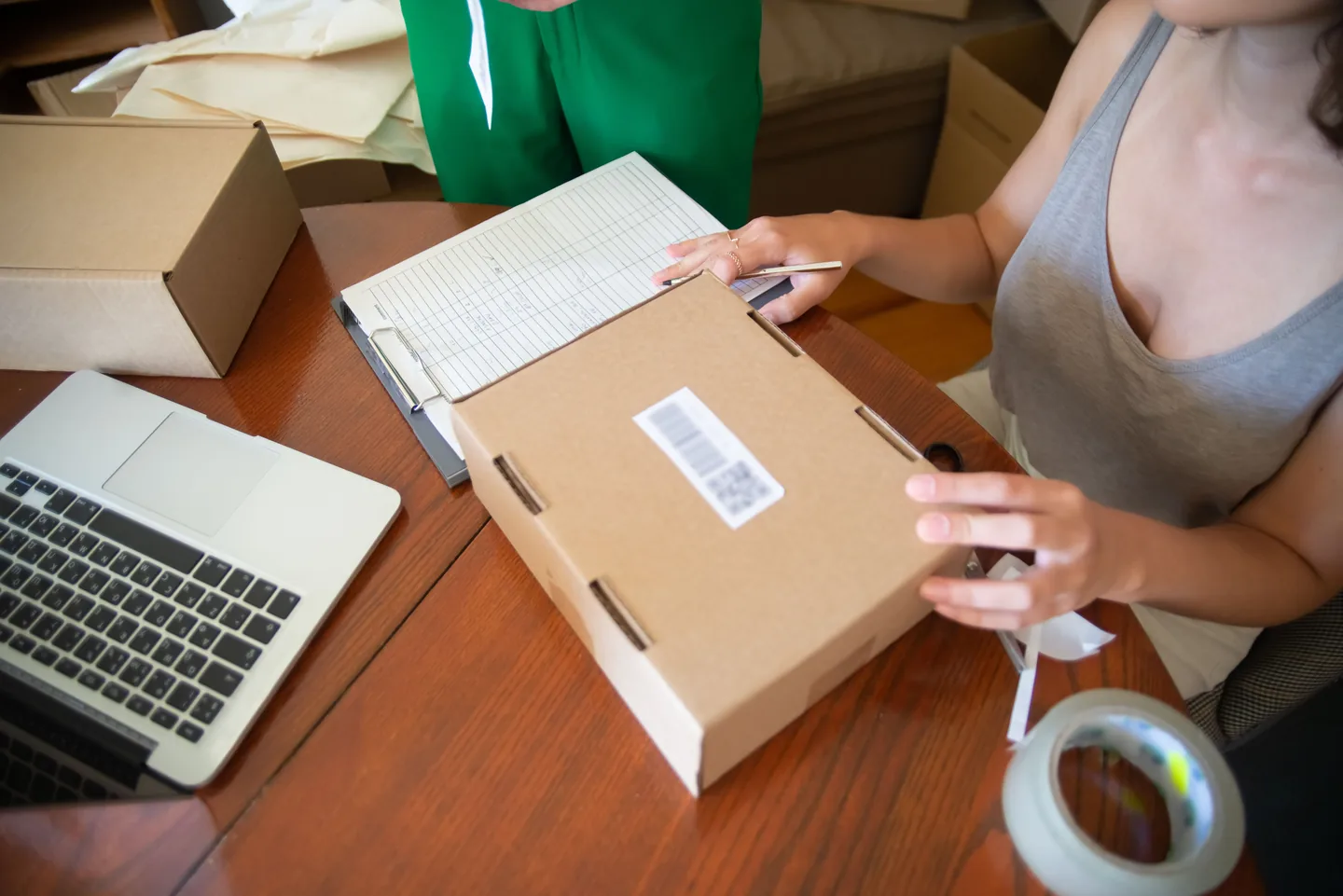 Mains vérifiant une liste à côté d’un carton et d’un ordinateur portable