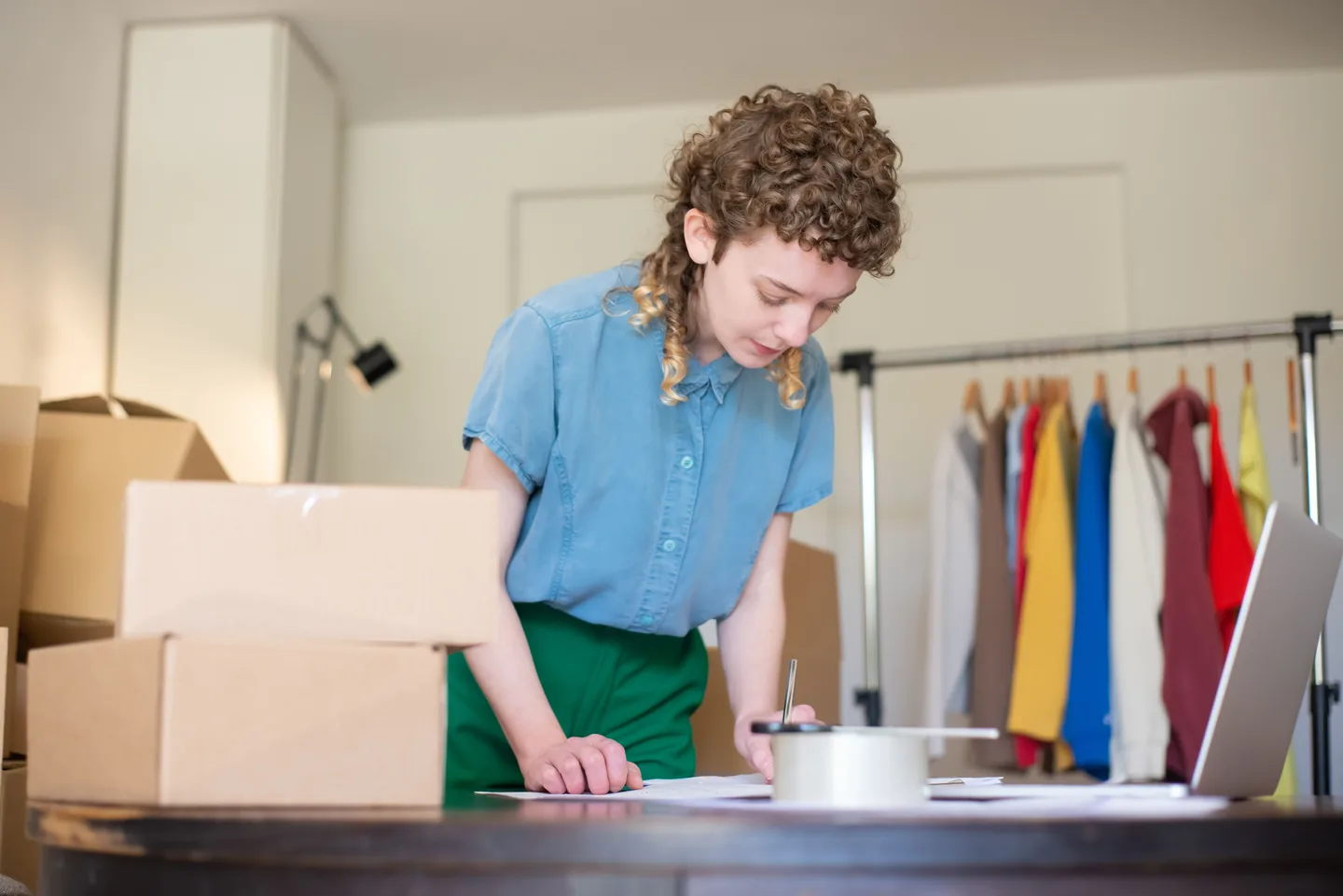 Femme traitant des commandes à un bureau près d’un portant à vêtements